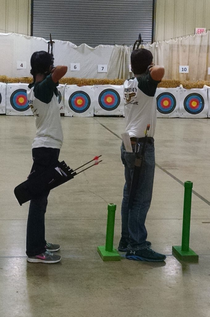 Two archery students lining up their shots on targets